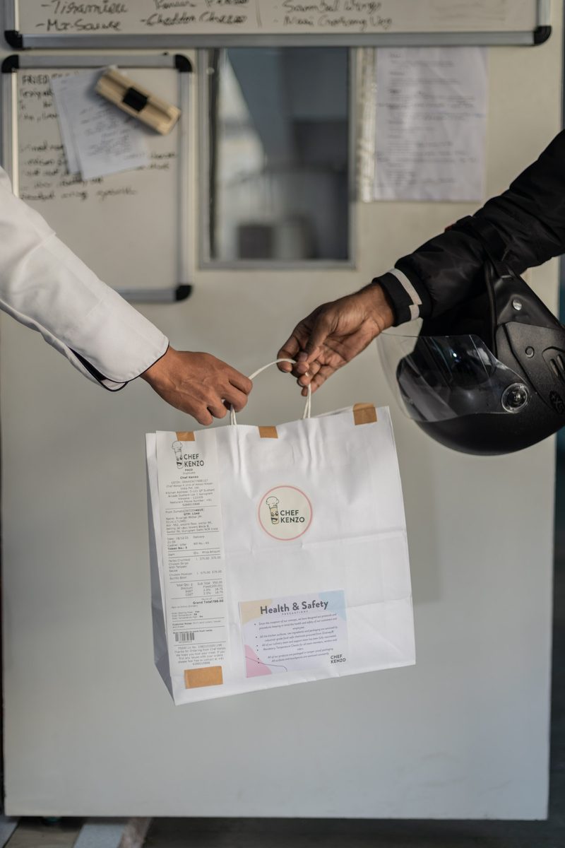 Chef Kenzo chef handing off branded delivery bag with Health and Safety panel